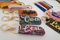 several keychains with different designs and words on them sitting on a white surface