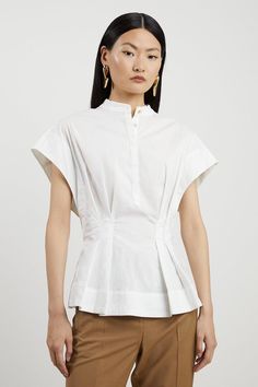 Feel Formal In Our Shirt, Made With High Quality Poplin Fabric, Featuring A Cinched Waist Which Flares At The Hips, And Wide Short Sleeves. This Piece Can Be Easily Paired With Anything From Tailored Trousers To Denim Jeans For Looks That Go From Office Days To Dinner Dates. Poplin Cap Sleeve Buttoned Pintuck Woven Shirt High Quality Poplin Fabric Flattering Cinched Silhouette Formal High Neckline Casual Short Sleeves Flared, Peplum Style Waist Women Shirt Designs Formal, Woven Tops For Women, Capped Sleeve Top, Tailored Shirts For Women, Casual Pintuck Short Sleeve Tops, Casual Short Sleeve Tops With Pintucks, Fitted Cotton Pleated Top, Casual Pleated Tops For Daywear, Fitted Pintuck Tops For Workwear