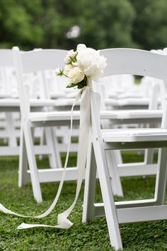 white chairs with bows and flowers tied to them in front of the aisle at a wedding