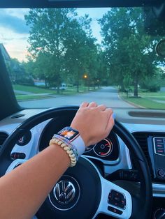 a person driving a car with their hand on the steering wheel and wristbands