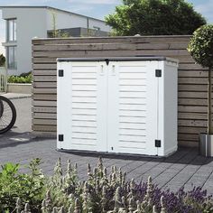 a white storage shed sitting next to a bicycle