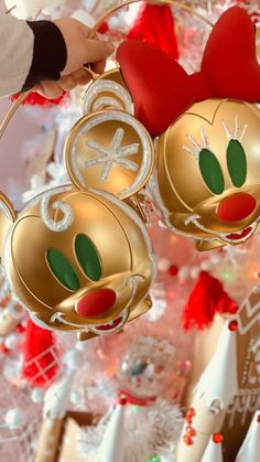 mickey and minnie mouse ornaments hanging from a christmas tree in front of a decorated holiday tree