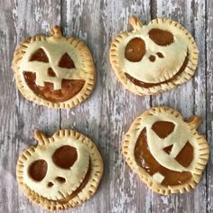 four pumpkin pies with faces on them sitting on a wooden table, one is cut in half and the other has been made to look like jack - o - o - lanterns