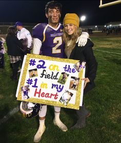 a man and woman holding a sign on the field