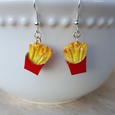 French Fries!  Now Dangle Earrings!  Everyone's favorite side dish to a Cheeseburger!!   Order your food jewelry today! These yummy handmade French Fry Earrings are in a Red Carton and slightly crinkled - just like the real thing! Mmm...  Fun Food Earrings for almost anyone!! The French Fries are handmade of polymer clay and dangle from surgical stainless steel ear wires. The French Fries measures almost 3/4" H. All items are packaged nicely in a jewelry box ready for gift giving! Silly Earrings, Weird Earrings, Charms Earrings, Miniature Food Jewelry, French Fry, Food Earrings, Funky Earrings, Food Jewelry, Favorite Side Dish