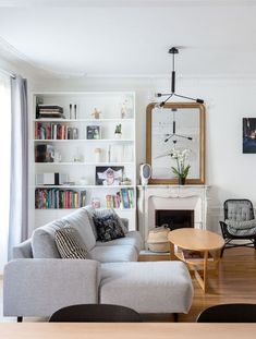 a living room filled with furniture and bookshelves next to a fire place on a hard wood floor