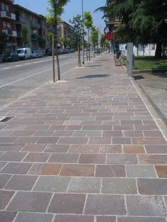 a brick sidewalk with trees and buildings in the background