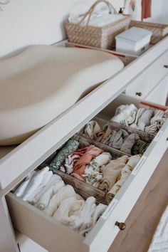 an open drawer in a white dresser with folded clothes and other items on the drawers