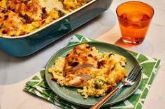 a green plate topped with chicken and rice next to a blue casserole dish