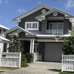 a gray house with white trim and two balconies