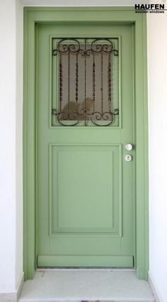 a green front door with wrought iron grills on the top and side panels above it