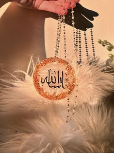 a person is holding up a necklace with the word allah written in arabic on it