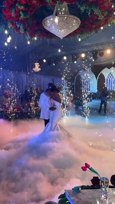 a bride and groom standing in the middle of a cloud filled dance floor