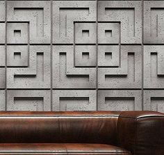 a brown leather couch sitting in front of a wall with squares on it's sides