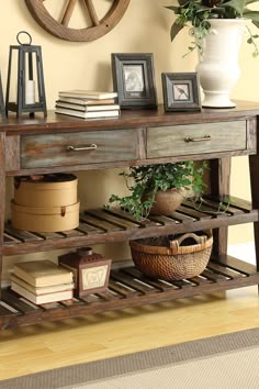 a wooden table with some books and pictures on it next to a potted plant