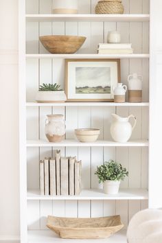 a white book shelf filled with books and vases