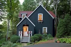 a black house with white trim on the front door and steps leading up to it