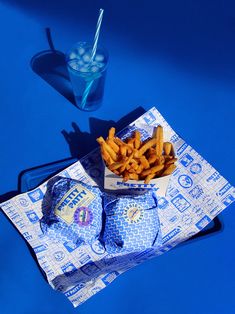 french fries are on a napkin next to a glass of water and a blue drink