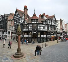 an old building with many windows and people walking on the sidewalk in front of it