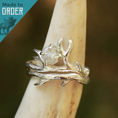 a silver ring sitting on top of a piece of wood with an antler branch design