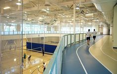 several people are playing basketball inside an indoor gym area with blue and white flooring