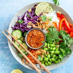 a white bowl filled with vegetables and chopsticks on top of a blue table