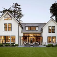 a large white house with lots of windows on it's side and grass in the front yard