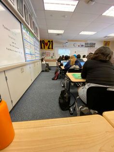 a classroom full of students sitting at their desks and writing on the whiteboard