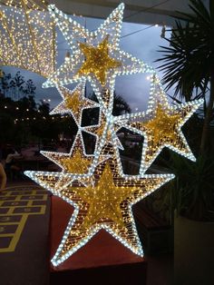 a large lighted star hanging from the ceiling in front of a building with lights on it