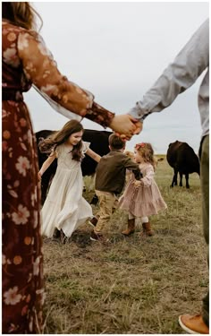 a group of people holding hands in front of some cows on a field with grass