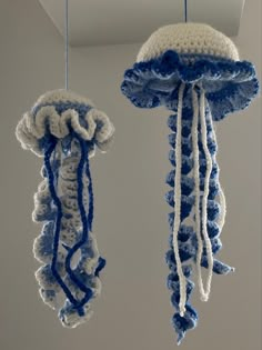 two blue and white crocheted jellyfish hanging from the ceiling in a room