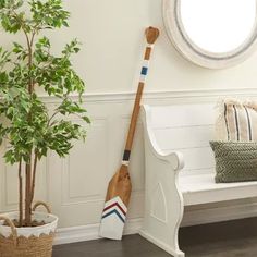 a wooden paddle leaning against the wall next to a white bench and potted plant