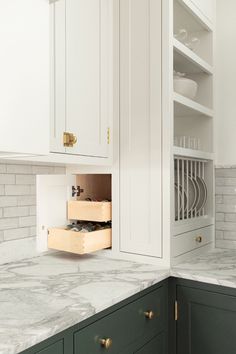 a kitchen with marble counter tops and white cupboards on the wall, open drawers