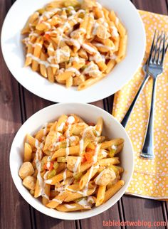 two white bowls filled with pasta and chicken