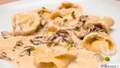 a white plate topped with ravioli covered in mushroom sauce