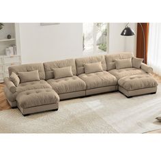 a large sectional couch in a living room with white rugs and wooden flooring