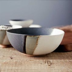 three black and white bowls sitting on top of a wooden table