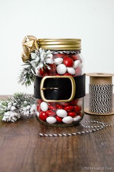 a jar filled with red and white candies next to a spool of twine