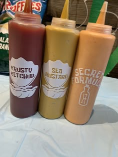 three ketchup bottles sitting on top of a table next to each other,