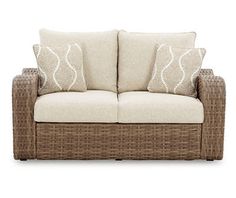 a wicker couch with two pillows on it