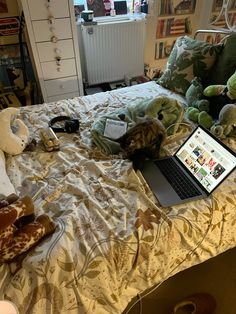 a laptop computer sitting on top of a bed next to stuffed animals and teddy bears