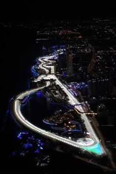 an aerial view of a city at night with light trails on the road and buildings in the background