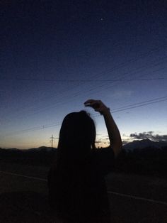 a woman is flying a kite in the air at night with mountains in the background