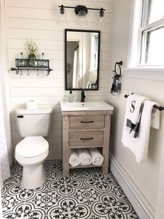 a white toilet sitting next to a sink in a bathroom under a mirror and towel rack