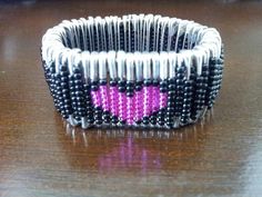 a beaded bracelet with a pink heart on the front and black beads on the back