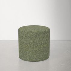 a green round ottoman sitting on top of a table