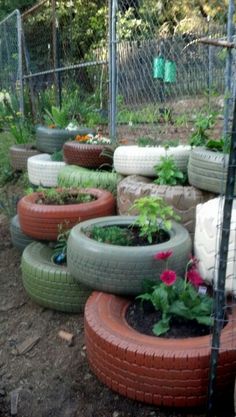 a bunch of tires that are sitting on the ground in front of some plants and flowers