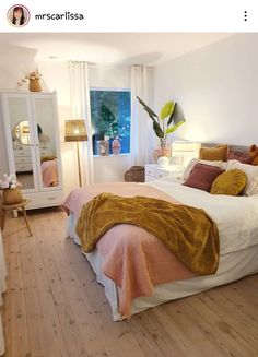 a bedroom with white walls and wooden floors has an orange blanket on the headboard