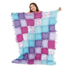 a woman is holding up a blanket made out of squares and fringes on it