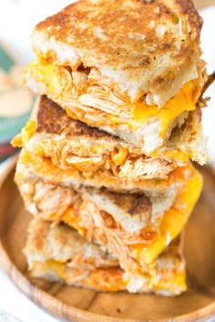 three grilled chicken sandwiches stacked on top of each other in a wooden plate with cheese